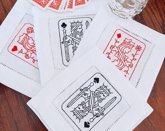 Peut inclure: Quatre serviettes de cocktail en lin blanc avec des motifs de cartes à jouer brodés. Les motifs comprennent une reine de carreau, un valet de pique, un roi de trèfle et une reine de pique.