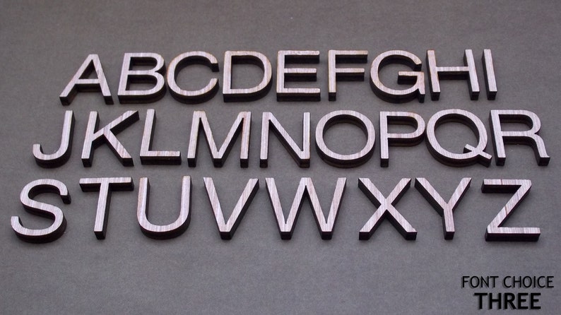 May include: A complete set of uppercase English alphabet letters from A to Z, crafted from dark wood with a visible grain texture. The letters are arranged in three rows, and the text FONT CHOICE THREE is printed in the bottom right corner.