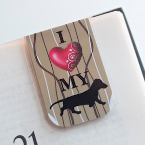 May include: A brown and white bookmark with a red heart and the text "I love my" and a black silhouette of a dachshund.