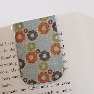 Könnte beinhalten: Ein Lesezeichen aus Stoff mit einem Muster aus blauen, grünen und orangen Kreisen. Das Lesezeichen befindet sich in einem Buch.
