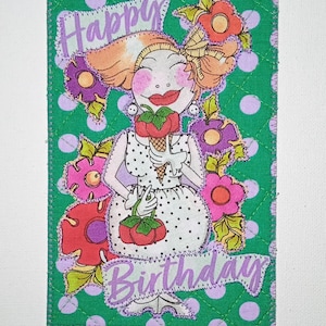 May include: A rectangular fabric greeting card featuring a green background with purple polka dots. A cartoon character in a white polka dot dress holds an ice cream cone and a basket of red fruit, surrounded by colorful flowers and the text Happy Birthday.