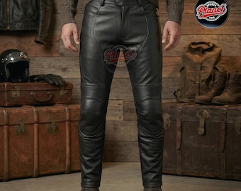 May include: Black leather motorcycle pants with ribbed knee and thigh details. The pants have a classic five-pocket design and a zip fly. The model is wearing brown boots. The background includes a leather jacket, helmet, and luggage.