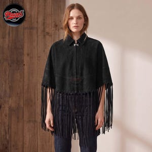 Women's genuine suede leather fringe western boho cape poncho — A black suede cape featuring a collared neckline, a silver-toned metal clasp closure at the neck, and long fringe detailing along the hemline. The garment has a structured shoulder desig