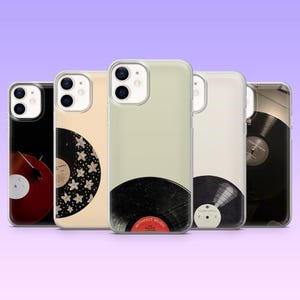Op de afbeelding: Een verzameling van vijf transparante telefoonhoesjes met vinylplaatontwerpen. De hoesjes hebben zwarte en rode platen, sommige met witte bloempatronen en één met de tekst "WITHOUT MUSIC". De hoesjes worden weergegeven tegen een paarse gradiëntachtergrond.