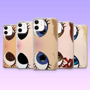 Può includere: Cinque cover trasparenti per telefono con illustrazioni stilizzate di grandi occhi espressivi. Ogni cover mostra un colore degli occhi diverso, tra cui marrone, nero, blu, nocciola e blu scuro, con ciglia dettagliate e accenti stellati.