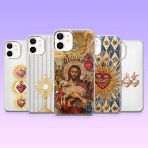 May include: A collection of phone cases featuring religious imagery. Designs include a heart with flames, a gold monstrance, a painting of Jesus with a lamb, and other sacred heart illustrations. The cases are clear with various colorful designs.