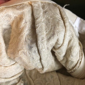 May include: Close-up of the inside of a white lace garment, showing the delicate stitching and fabric.