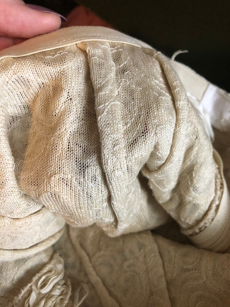 May include: Close-up of the inside of a white lace garment, showing the delicate stitching and fabric.
