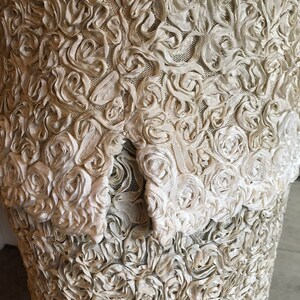 May include: A white dress with a textured fabric made of small, raised rosettes.