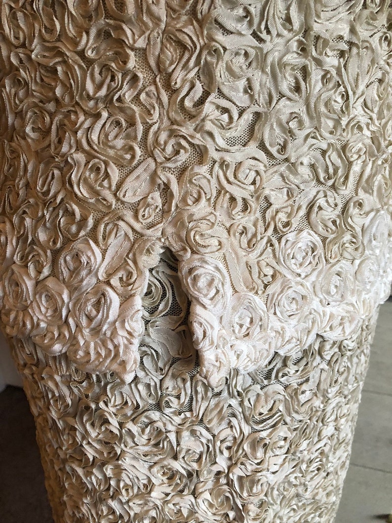 May include: A white dress with a textured fabric made of small, raised rosettes.