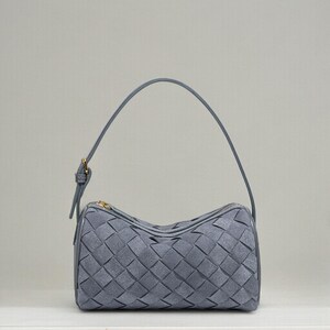 Puede incluir: Un bolso gris con dise&ntilde;o trenzado. El bolso tiene forma redondeada, cierre de cremallera y una fina correa para el hombro. Los herrajes son de color dorado.