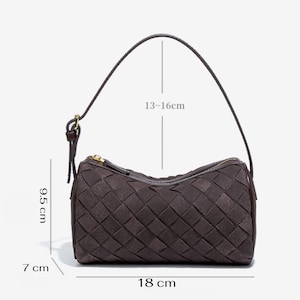 Puede incluir: Bolso de mano tejido marr&oacute;n oscuro con asa superior y cremallera dorada. El bolso mide 7 cm de ancho, 18 cm de largo y 9,5 cm de alto. La altura del asa es de entre 13 y 16 cm.