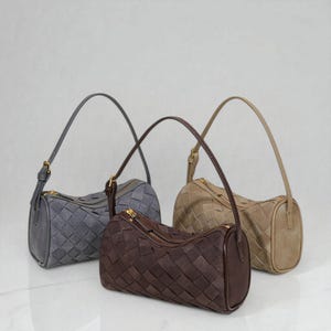 Puede incluir: Tres bolsos de hombro de estilo tejido en gris, marr&oacute;n y beige. Cada bolso tiene forma cil&iacute;ndrica, cremallera superior y asa a juego. Los bolsos est&aacute;n hechos de un material similar al ante y tienen herrajes dorados.