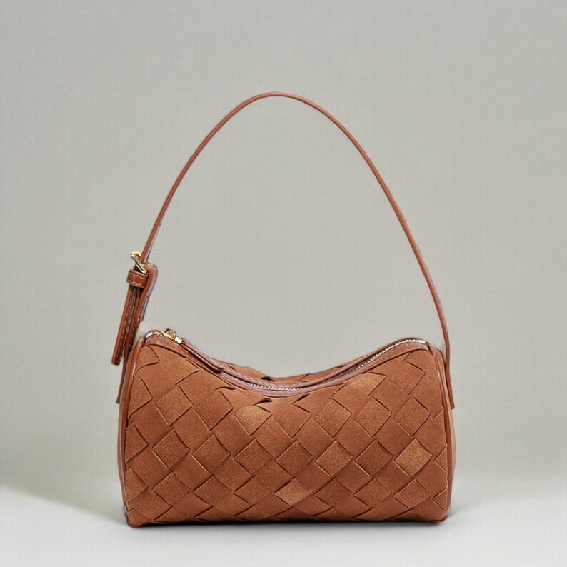 Puede incluir: Un bolso marr&oacute;n tejido con una sola correa para el hombro. El bolso tiene forma rectangular con cierre de cremallera y un patr&oacute;n tejido. La correa es fina y est&aacute; hecha de material marr&oacute;n a juego.