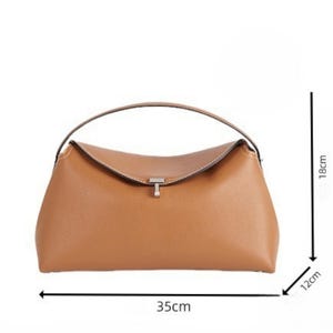 Pu&ograve; includere: Una borsa in pelle marrone chiaro con manico superiore e chiusura a patta. La borsa &egrave; lunga 35 cm, alta 18 cm e larga 12 cm. La borsa ha una chiusura color argento e cuciture bianche.