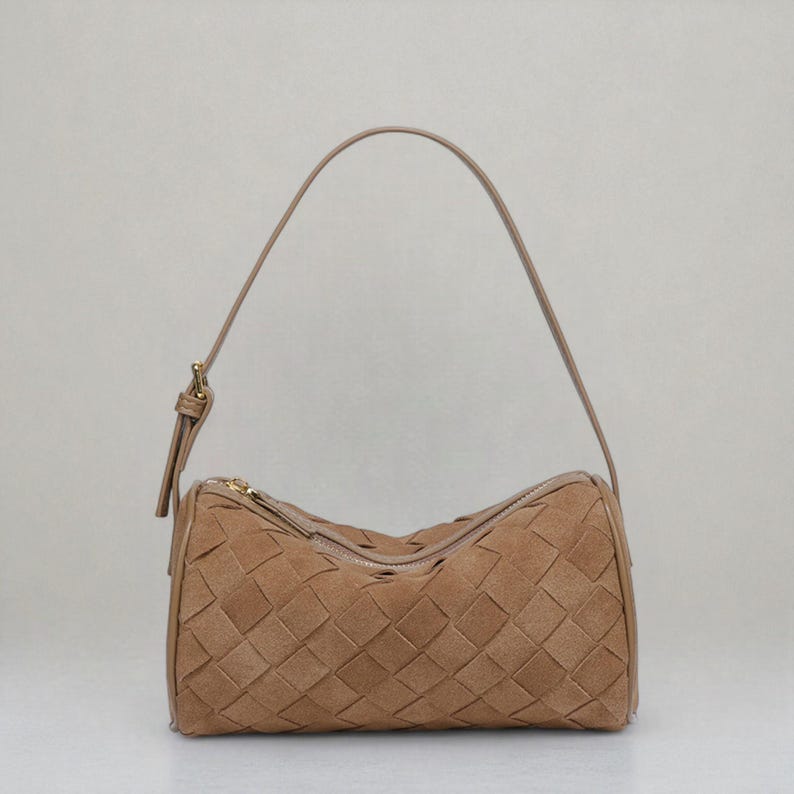 Puede incluir: Un bolso de mano de cuero tejido de color marr&oacute;n claro, con forma cil&iacute;ndrica. El bolso tiene un cierre de cremallera y una fina correa de hombro ajustable. El patr&oacute;n tejido crea una apariencia texturizada. El bolso est&aacute; dise&ntilde;ado para llevar lo esencial.