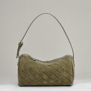 Puede incluir: Bolso de mano de ante verde oliva con dise&ntilde;o tejido. El bolso tiene forma cil&iacute;ndrica, cierre de cremallera y una sola correa para el hombro. Los herrajes son dorados.