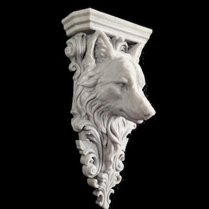 May include: A light grey wall corbel featuring a sculpted wolf head integrated into ornate, swirling acanthus leaf carvings. The architectural support piece has a flat, rectangular top section and tapers downwards into a decorative pointed base.