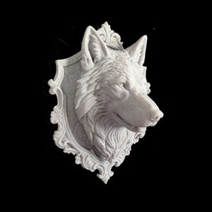Può includere: Un supporto da parete tridimensionale grigio chiaro raffigurante la testa scolpita di un lupo. La testa del lupo è centrata su una placca ovale ornata con intricati dettagli a volute lungo i bordi, creando un elemento decorativo in rilievo.