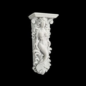 Puede incluir: Una ménsula de pared blanca que presenta una figura de sirena esculpida con cabello largo y fluido y una cola de pez. El elemento arquitectónico decorativo tiene un estante superior plano y tallas intrincadas de olas y follaje alrededor.