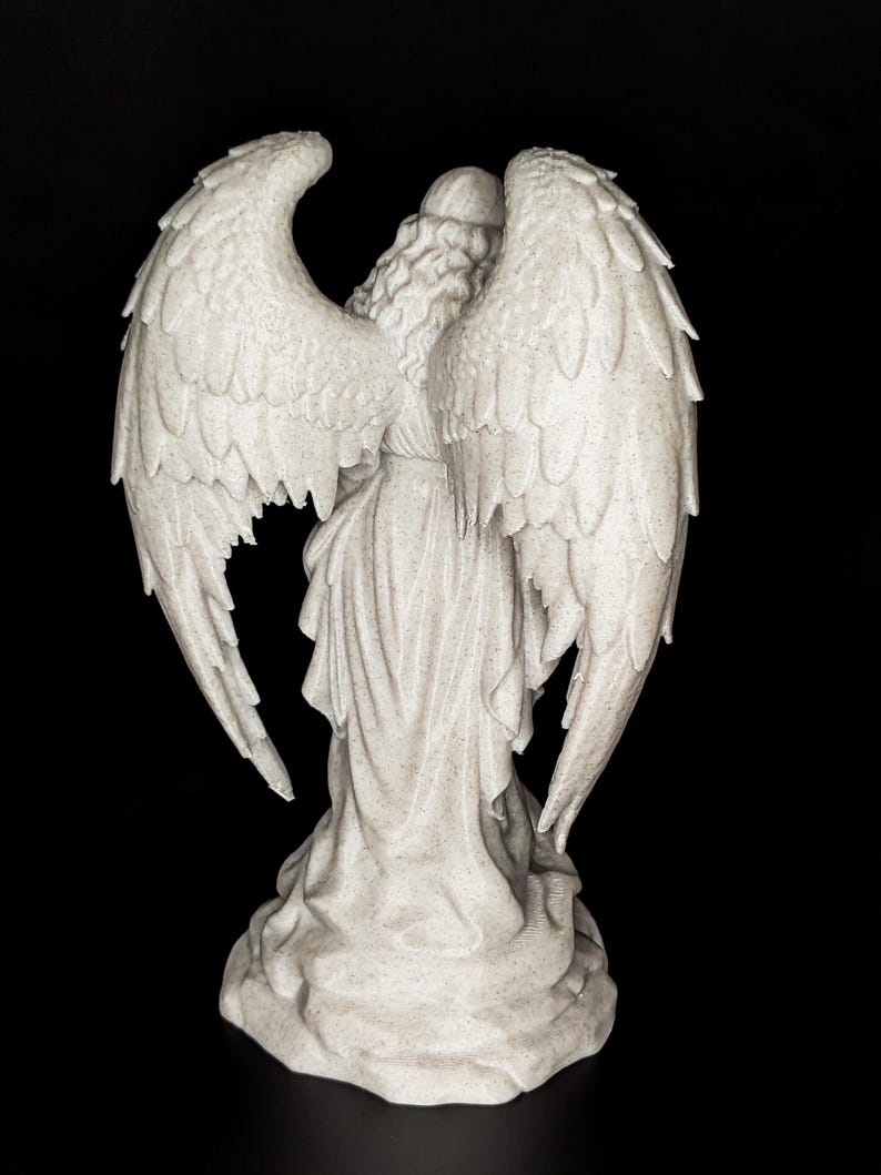 May include: A detailed, rear view of a white angel statue with large, textured wings. The angel is wearing a flowing gown and has long, wavy hair. The statue is set against a black background.