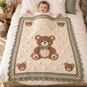 May include: A cream-colored crochet baby blanket featuring a large central brown teddy bear with a green bow tie, surrounded by four smaller bear faces in the corners. The blanket has a scalloped green border and white bobble stitch accents.