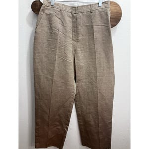 May include: High-waisted trousers in a solid tan color with a visible textured weave. These pants feature a structured waistband with belt loops, a center front zipper fly closure, and a clean, straight-leg silhouette with pressed creases.