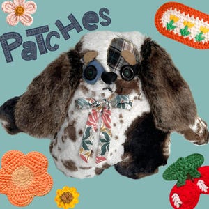 May include: A handmade plush dog with brown and white fur, button eyes, and a patterned bow. The word "Patches" is stitched above the dog. Crochet flowers and a decorative strip are scattered around the dog.