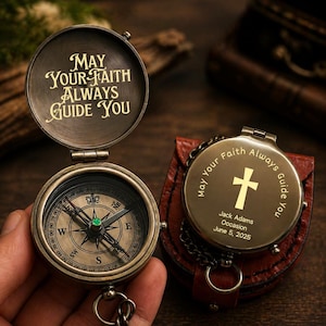 May include: An open antique brass compass with the inscription "MAY YOUR FAITH ALWAYS GUIDE YOU" on the lid. The compass face shows directional markings. A second compass is closed, with a cross and the inscription "May your Faith Always Guide You".