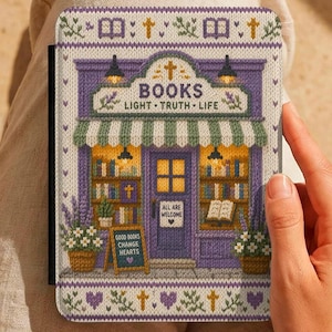 Può includere: Una copertina di libro con un design di libreria viola, con le parole "BOOKS LIGHT TRUTH LIFE". La copertina ha un aspetto a maglia con motivi floreali e a croce. Un piccolo cartello recita "ALL ARE WELCOME."