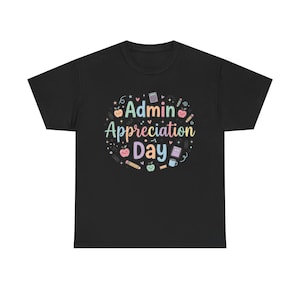May include: A black short-sleeved t-shirt featuring a central graphic with the text Admin Appreciation Day in pastel colours. The design is surrounded by small illustrations of apples, pencils, a calculator, a notebook, and a coffee mug.