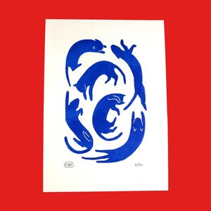May include: A print featuring a collection of stylized blue cats in various poses on a white background. The artwork is set against a red backdrop. The print is numbered 21/50 and includes an artist's signature.