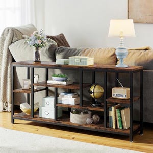 May include: A rustic console table with a dark metal frame and distressed wood shelves. The table is filled with decorative items, including a lamp, books, boxes, a globe, and a small radio. The table is placed in front of a sofa.