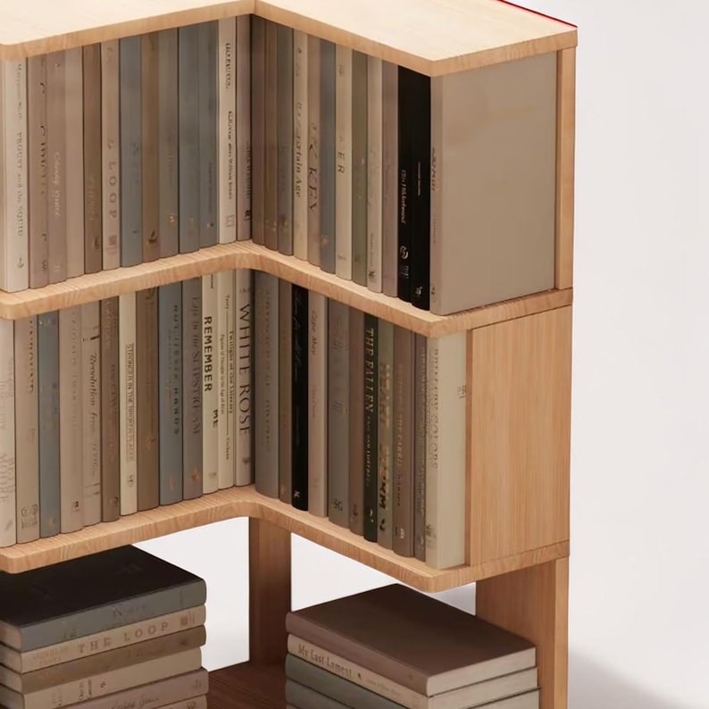 K&ouml;nnte beinhalten: Ein B&uuml;cherregal aus Holz mit einem einzigartigen, eckigen Design. Die Regale sind mit einer Vielzahl von B&uuml;chern in neutralen T&ouml;nen gef&uuml;llt, was eine minimalistische &Auml;sthetik schafft. Das B&uuml;cherregal ist aus hellem Holz gefertigt.