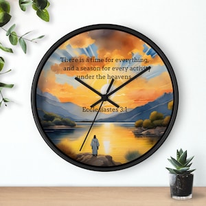 May include: Round wall clock with a black frame, displaying a landscape scene with a lake, mountains, and a sunset. The clock face has the text "There is a time for everything, and a season for every activity under the heavens. Ecclesiastes 3:1."