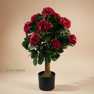 May include: An artificial topiary tree featuring deep red flowers and green foliage. The tree is set in a black pot with a textured brown trunk. The image includes the text "Leaf Habitat Premium Leaf".
