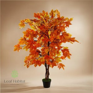 May include: Artificial maple tree with bright orange and yellow leaves. The tree has a brown trunk and is potted in a black pot. The leaves are detailed and create a full, autumn-themed display. The logo "Leaf Habitat" is visible.
