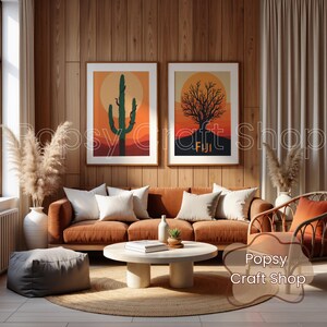 May include: Two framed art prints with desert landscape scenes hang above a rust-colored sofa with white pillows. One print features a cactus, the other a tree, both against a sunset backdrop. The room has wooden paneling and a round coffee table.