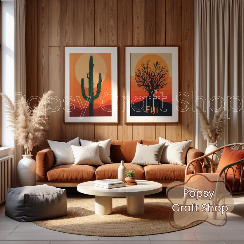 May include: Two framed art prints with desert landscape scenes hang above a rust-colored sofa with white pillows. One print features a cactus, the other a tree, both against a sunset backdrop. The room has wooden paneling and a round coffee table.