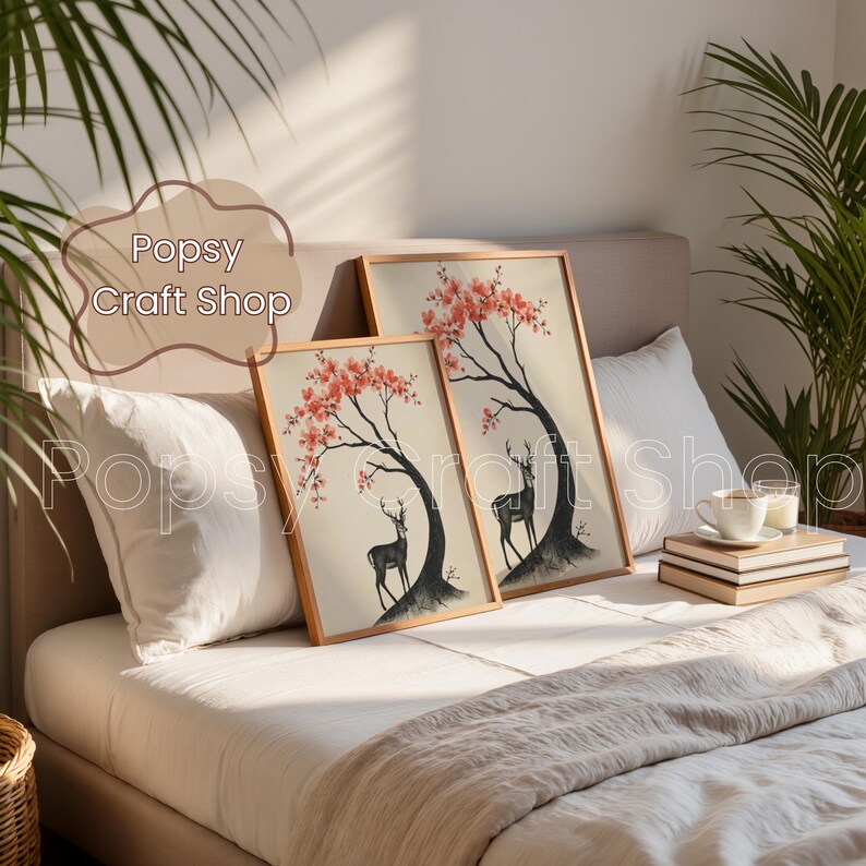 May include: Two framed art prints featuring a black deer under a tree with red blossoms. The prints are displayed on a bed with white pillows and a beige blanket. The text "Popsy Craft Shop" is visible in the image.