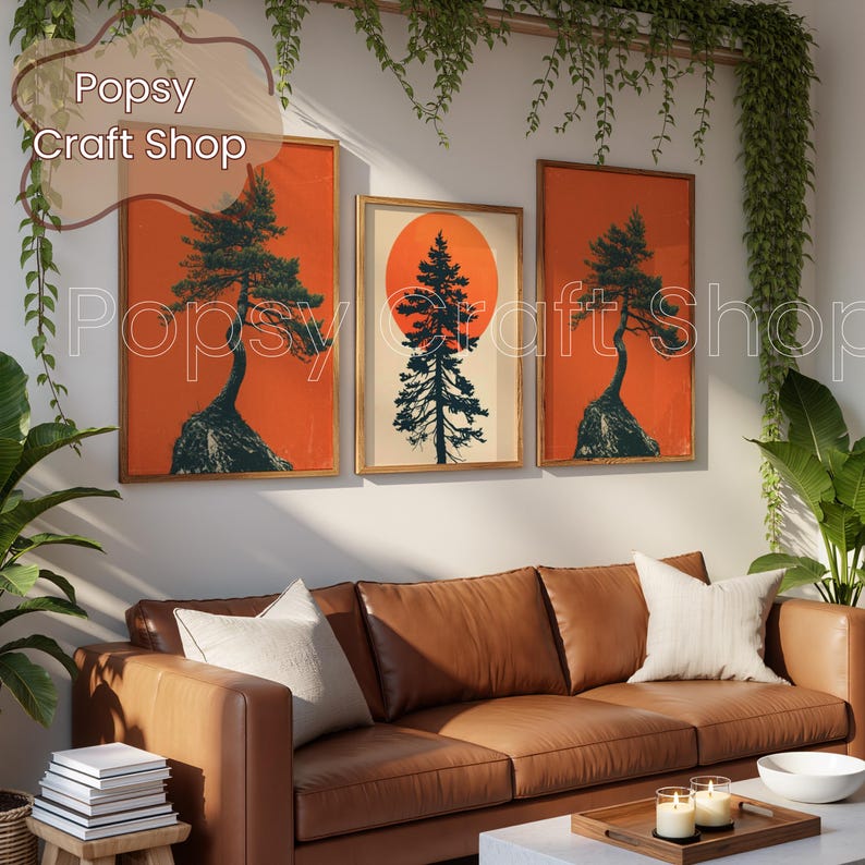 May include: Three framed art prints featuring a tree silhouette against a vibrant orange background. The middle print showcases a tree in front of a large orange sun. The prints are displayed above a brown leather sofa, creating a warm and inviting atmosphere.