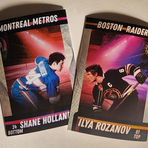 May include: Two hockey trading cards. One card reads "MONTREAL METROS" and features "Shane Holland" with the number 24. The other card says "BOSTON RAIDERS" with "Ilya Rozanov" and the number 81. Both cards show hockey players in action on the ice.