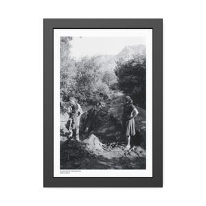 Puede incluir: Fotografía en blanco y negro enmarcada de dos personas de pie cerca de una gran formación rocosa en un entorno natural. La fotografía es una imagen vintage, con árboles y montañas al fondo. La imagen está en un marco negro.