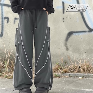 Może przedstawiać: Ciemnoszare spodnie cargo z białymi liniami akcentującymi i kieszeniami. Spodnie mają talię ze sznurkiem i są częścią kolekcji Isabel Street Wear. Spodnie mają szerokie nogawki i mają swobodny styl uliczny.