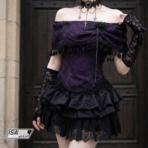 May include: A purple and black off-the-shoulder dress featuring a damask pattern, a layered ruffled skirt with lace trim, and a bodice with hanging chain details. The outfit includes black lace fingerless gloves and a matching choker necklace.