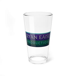 Puede incluir: Un vaso de pinta transparente con el texto "RYAN EAISE PRODUCTIONS" en letras moradas y blancas sobre una banda verde y turquesa. El vaso está vacío y sobre una superficie blanca.