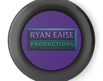 May include: A circular black button with a purple centre. The centre has a rectangular design with the text "RYAN EAISE PRODUCTIONS" in silver and teal lettering.
