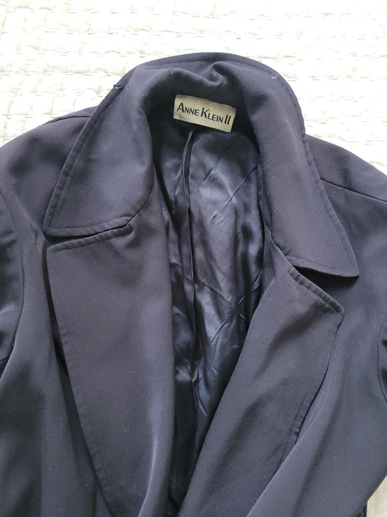 May include: A navy blue blazer with a label that reads "Anne Klein II" on the inside collar.