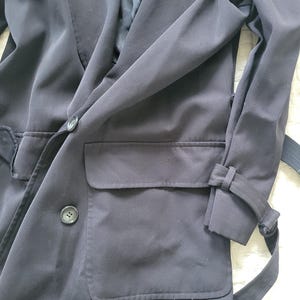 May include: A black long-sleeved jacket with a double-breasted closure, two large pockets, and a belt.