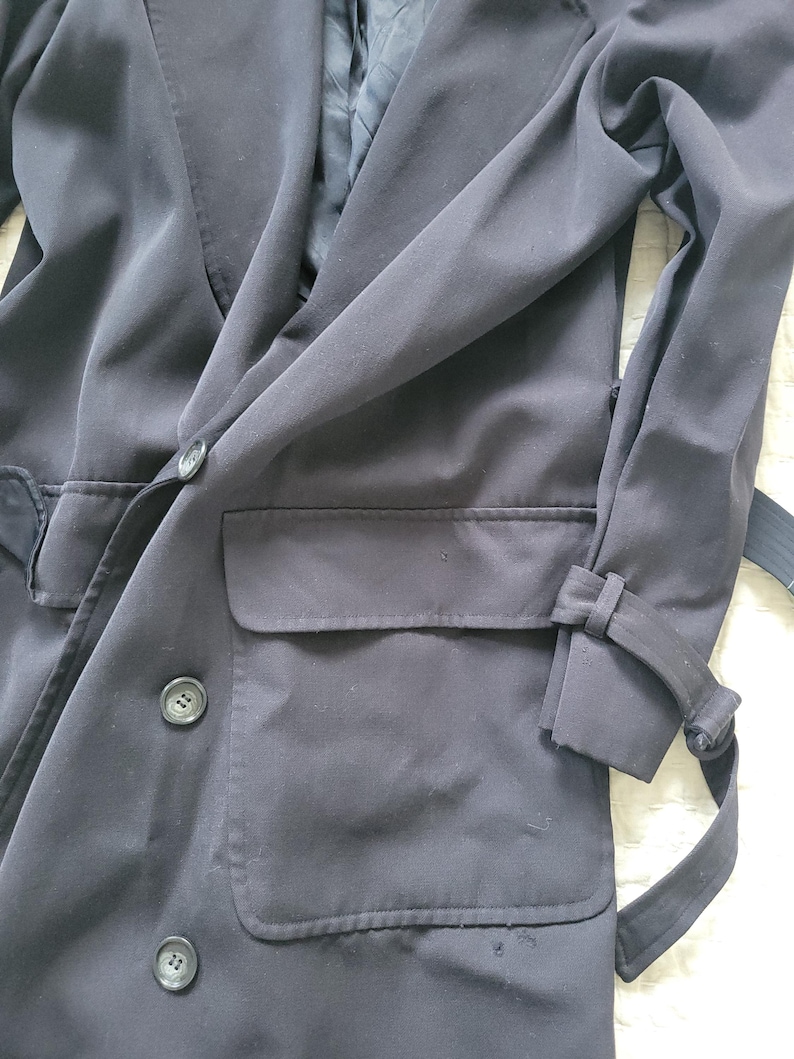 May include: A black long-sleeved jacket with a double-breasted closure, two large pockets, and a belt.